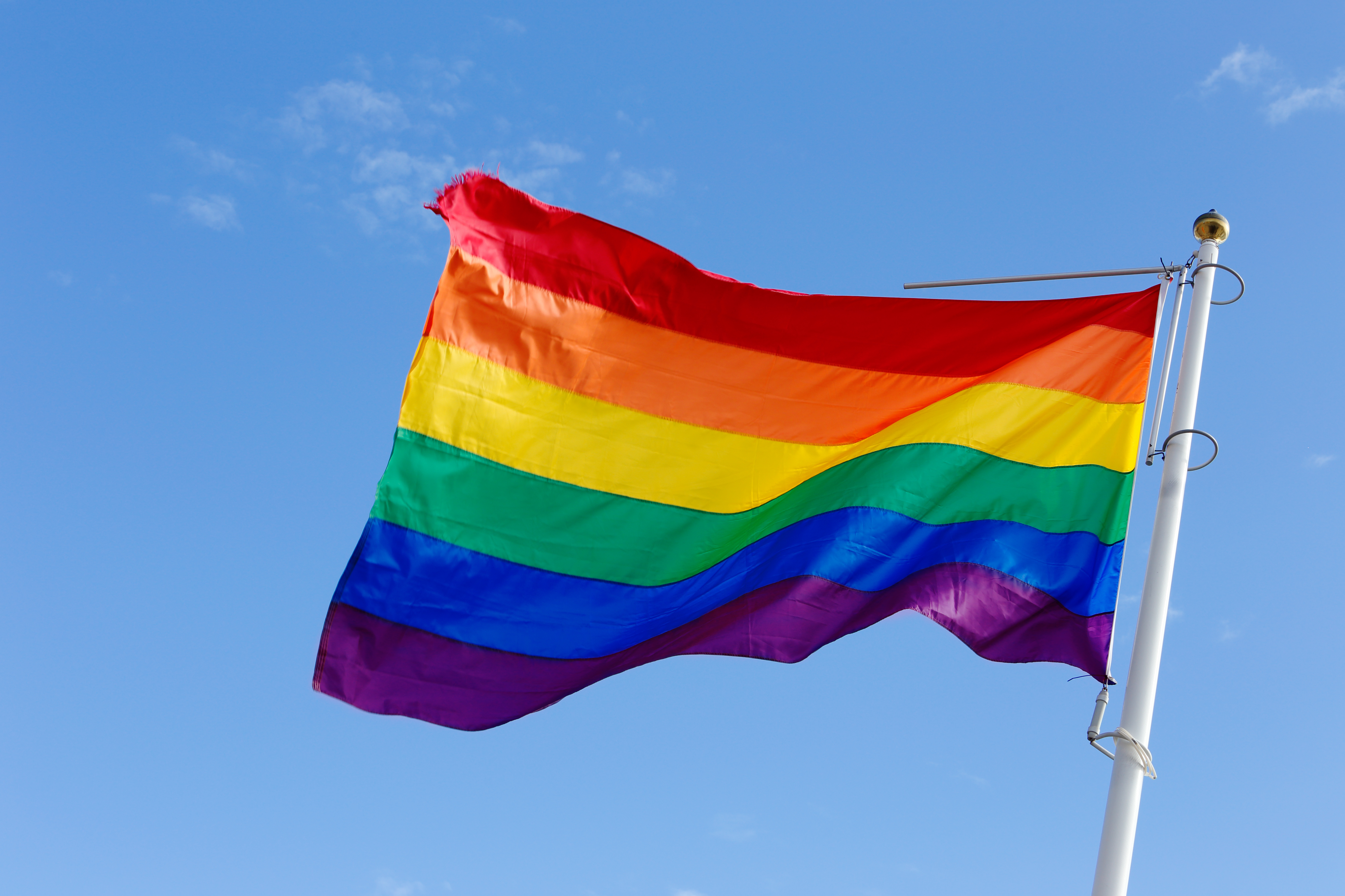 Close-up of a rainbow flag on blue sky.